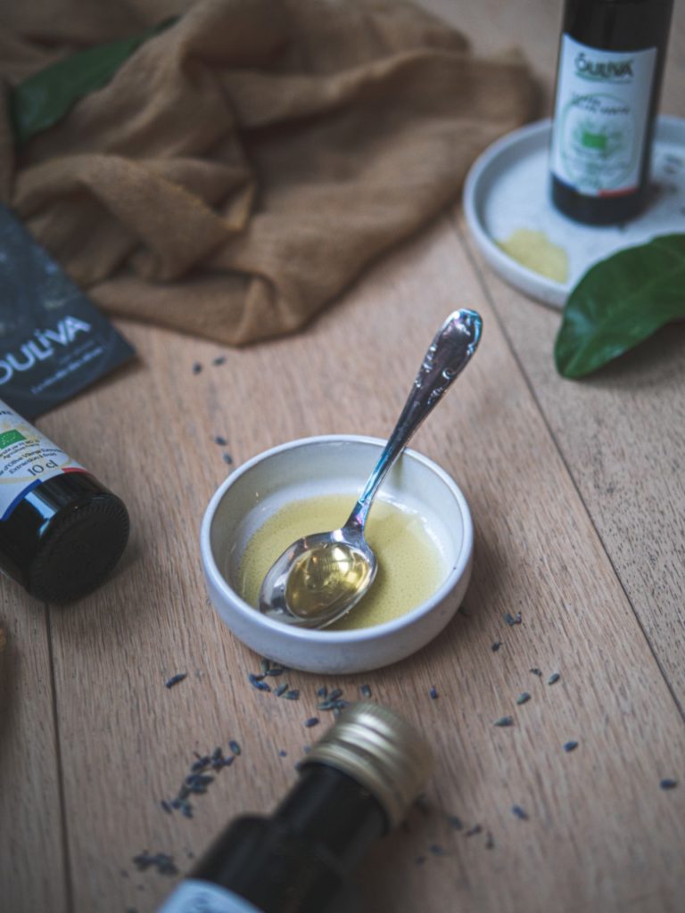 Petite cuillère remplie d'huile d'olive, récipients, tissus et lavande